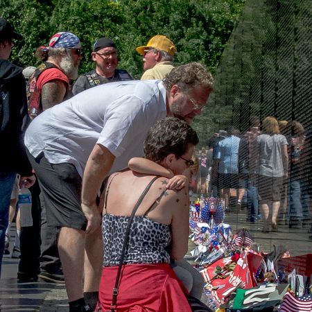 Family paying tribute to fallen soldiers at Vietnam Veterans Memorial Wall in Washington, D.C.