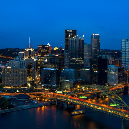 Pittsburgh Pennsylvania cityscape with skyscraper, bridge and river views by way of long exposure at night.