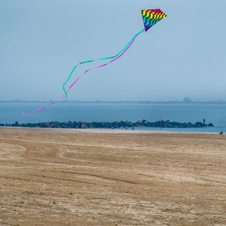 Child and mother flying kite on Coney Island beach, New York.