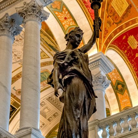 Great Hall of Library of Congress's Thomas Jefferson Building and bronze statue of woman holding a light torch.