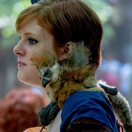 Parrot on shoulder of girl in costume for Maryland Renaissance Festival in Brownsville, Maryland.