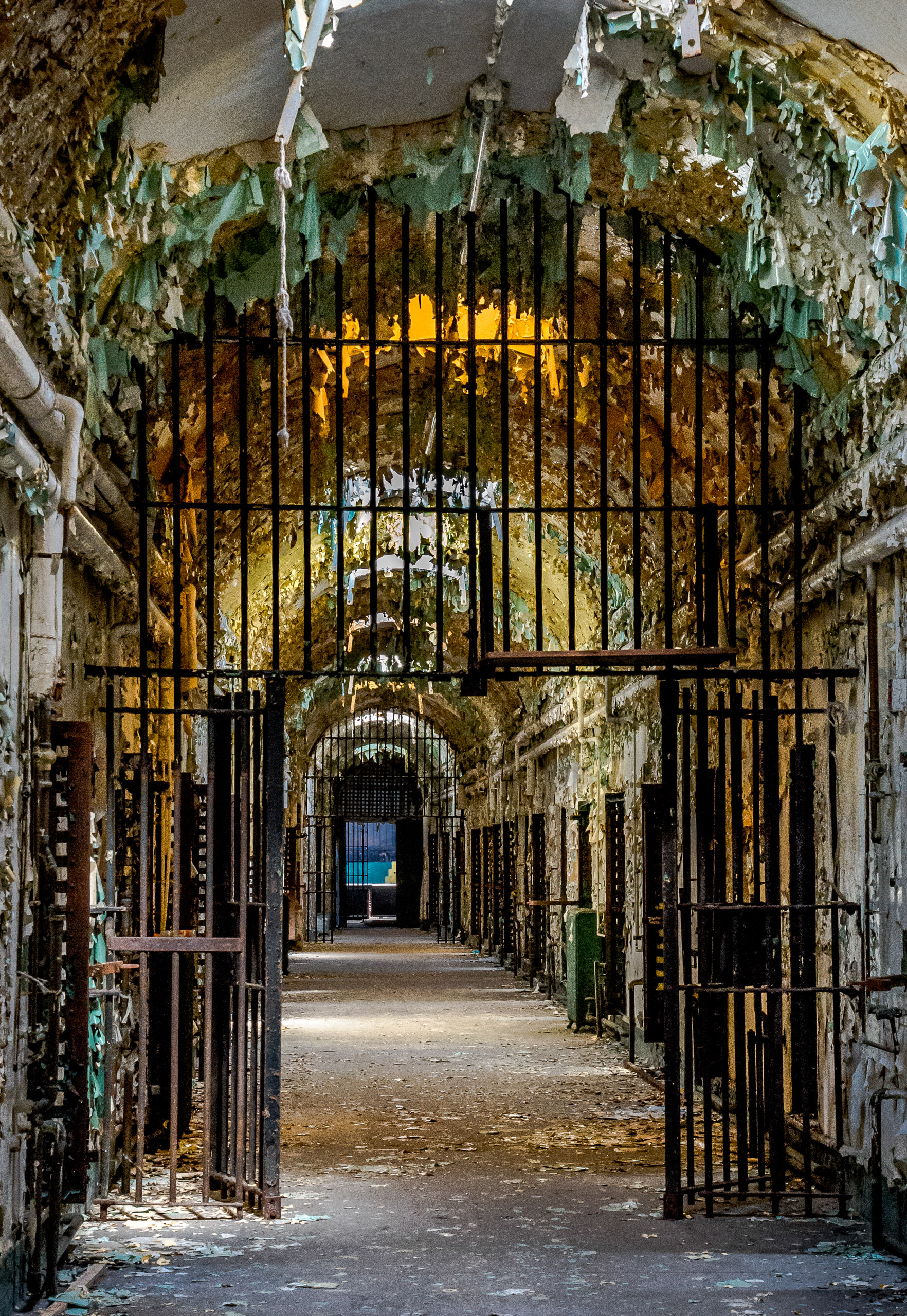 Abandoned Pennsylvania Holmesburg Prison cellblock with wrought iron entrance, peeling paint and barrel ceiling.