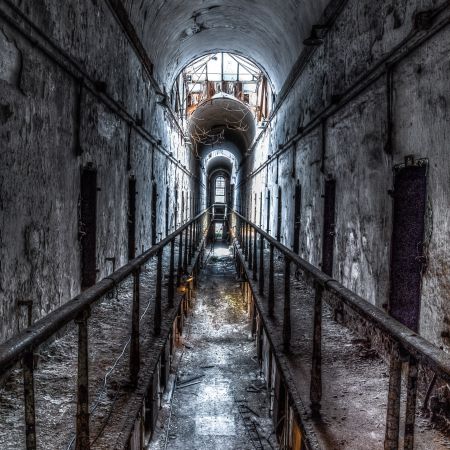 Abandoned elevated cell block with barrel ceiling, vines, skylights, vines and walkway at Eastern State Penitentiary Philadelphia Pennsylvania.