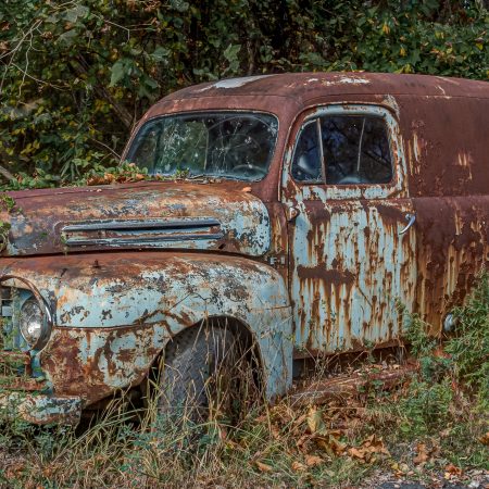 Classic 1940s Ford Utility truck van in weeds.