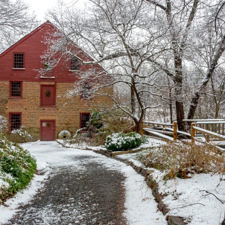 Winter landscape of Colvin Run Mill with trees and snow cover in Great Falls Virginia.