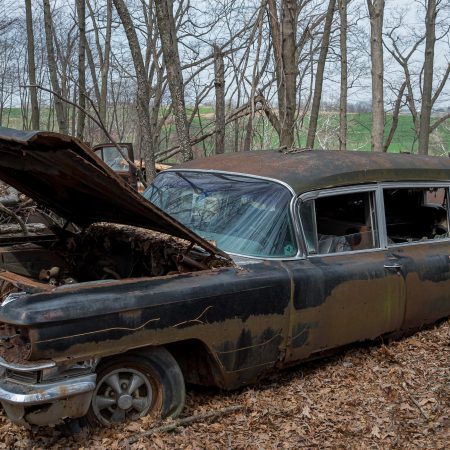 1960s Cadillac hearse with open hood and chrome mag wheels.