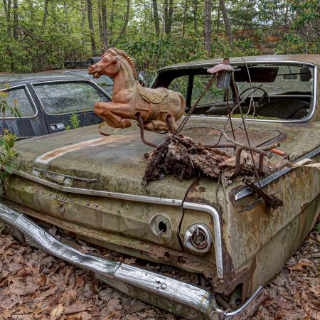 1960s Chevrolet Impala with Rocking Horse toy setting on top of trunk.