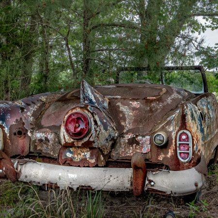 Vintage convertabe car with winged taillight in middle of trunk.