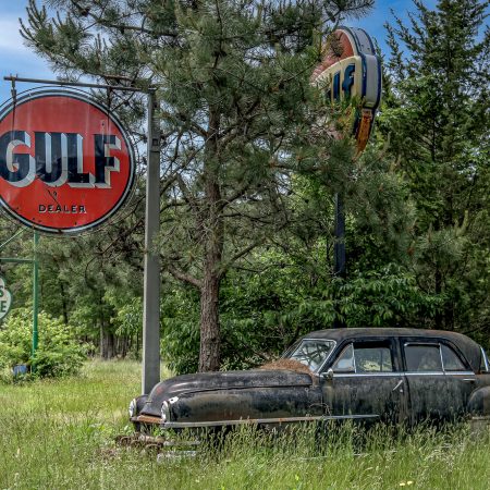 Vintage Chrysler Windsor Sedan with antique Gulf and Cities Service signs.