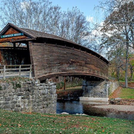 Fall scene of Humpback Covered Bridge with stream and mountains in Covington, Virginia.