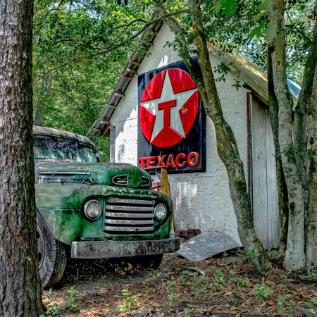 Vintage green Ford 1940s Truck next to classic Texaco sign.