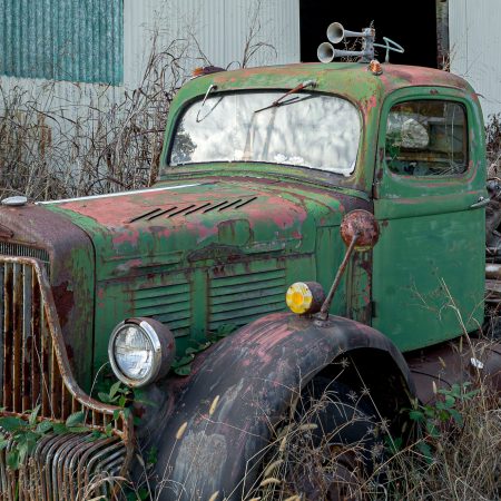 Vintage 1940s farm trucks with rust and multi-colored paint finish.