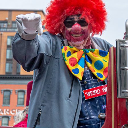 Portrait of Shriner Clown on firetruck wearing red fuzzy wig and white gloves.