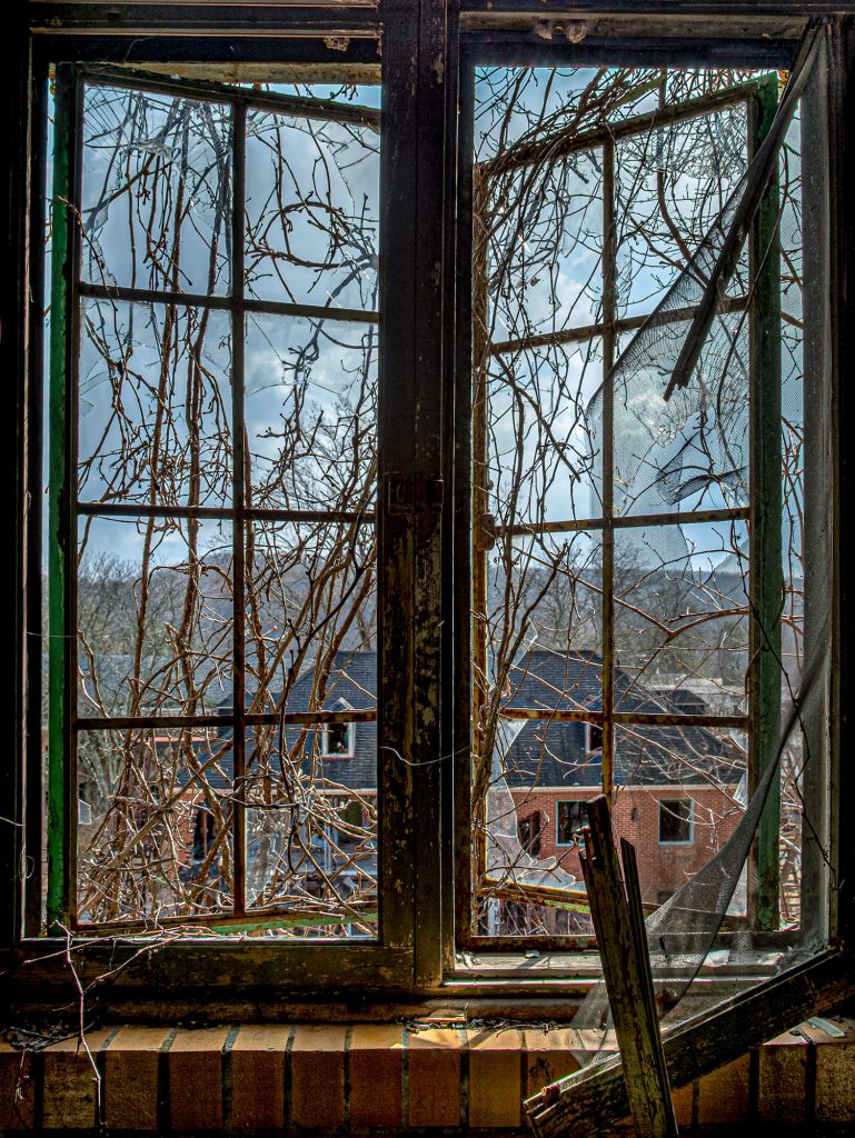 Forlorn Tuberculosis Asylum in Maryland with broken window view of hospital campus.