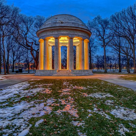 Illuminated World War I Memorial at blue hour with snow on the ground.