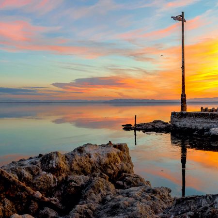 Sunset at Bombay Beach, Salton Sea, California with derelict salt crusted pier in foreground.