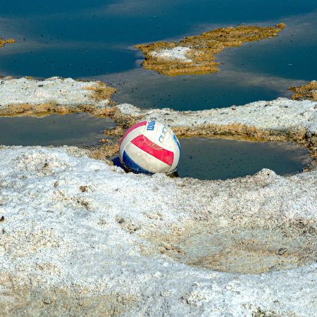 A soccer ball is held hostage in the pits of a polluted and chemical crusted Salton Sea California shoreline.