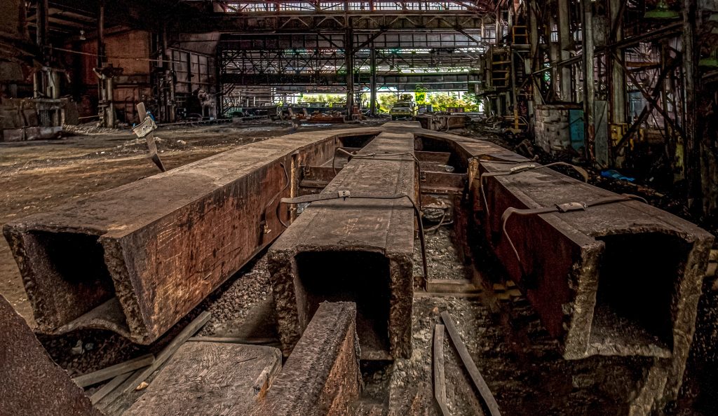 The large rusty steel structural support for the fallen World Trade Center Tower rests inside the abandoned Lukens Steel Rolling Mill.