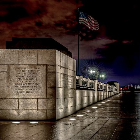 A ghostly woman stops to read Franklin Delano Rossevelt's tribute to WWII women at the World War II Memorial in Washington, D.C. with the Monument overlooking the site.